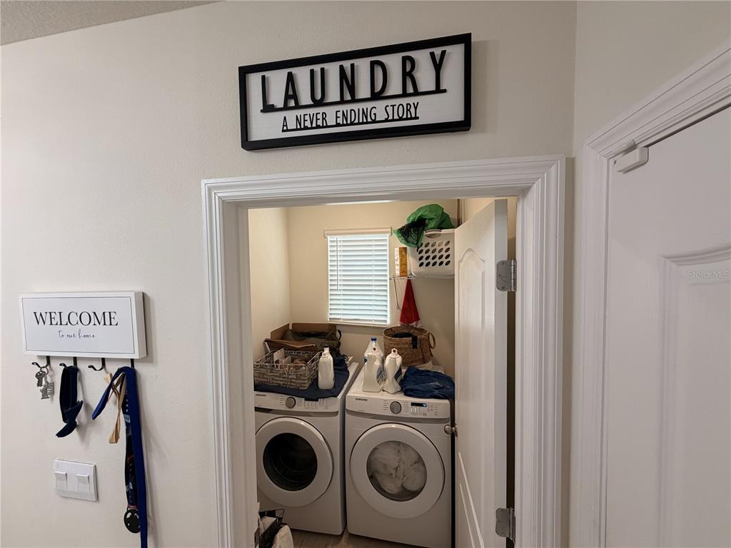 A laundry room features a front-loading washer and dryer beneath a window and shelving — 3925 ANGOLA LANE, SANFORD, FL