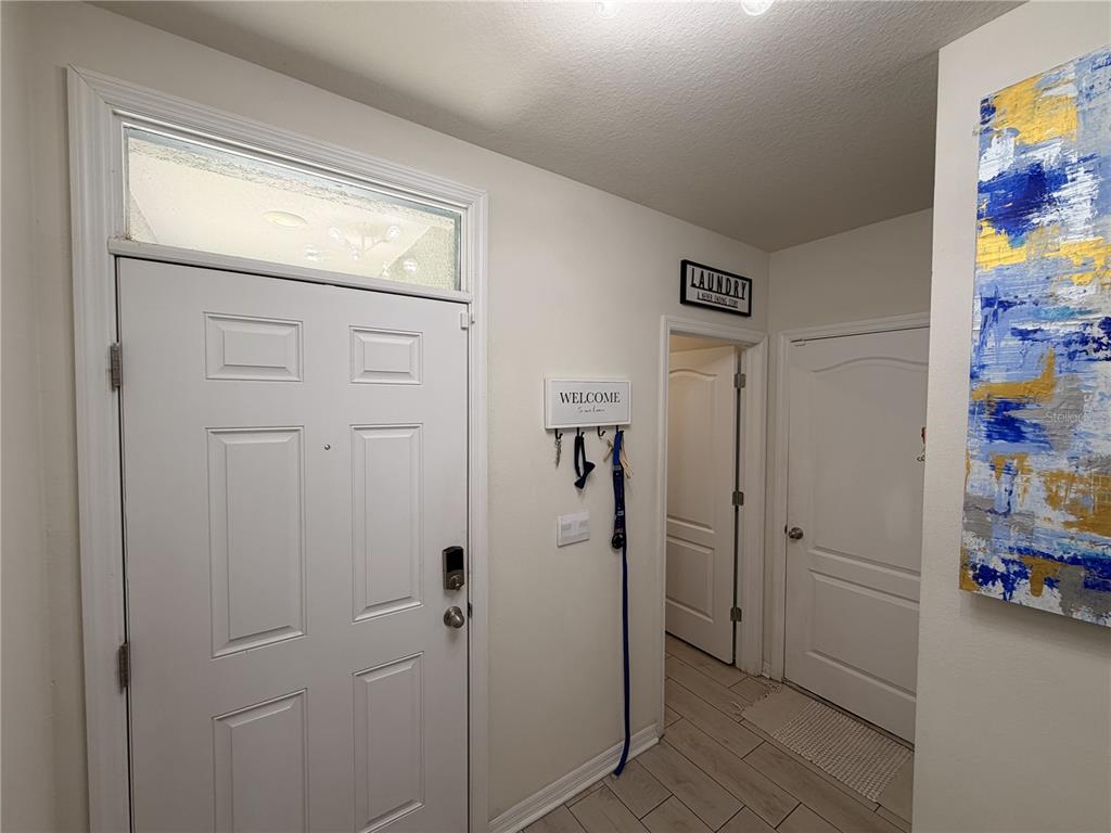 An entryway features a white front door with a transom window, tile flooring, and wall decor — 3925 ANGOLA LANE, SANFORD, FL