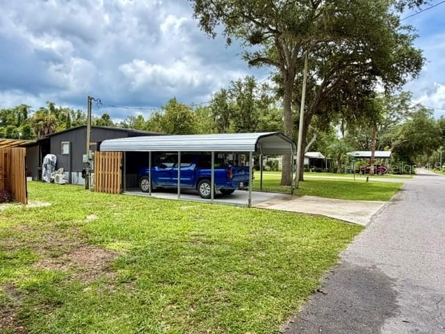 A blue pickup truck is parked under a metal carport next to a house — 11097 NW 114TH STREET, CHIEFLAND, FL