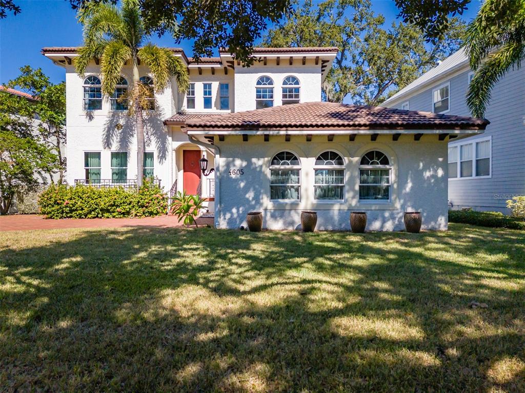 A two-story stucco house with a red tile roof and arched windows sits on grass — 4605 W VASCONIA STREET, TAMPA, FL