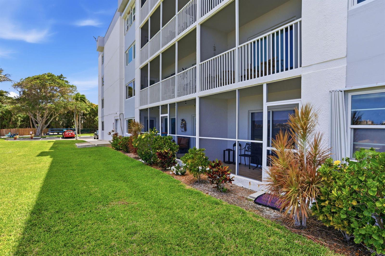 A multi-story apartment building features screened-in balconies overlooking a grassy lawn and landscaping — 1516 S Lakeside Drive # 103, FL 33460, FL