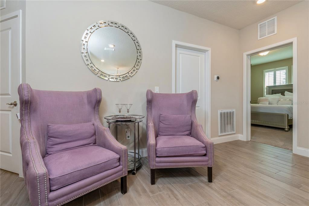 Two purple wingback chairs sit on a tiled floor in front of a round mirror — 7517 LAUREATE BOULEVARD UNIT 4103, ORLANDO, FL