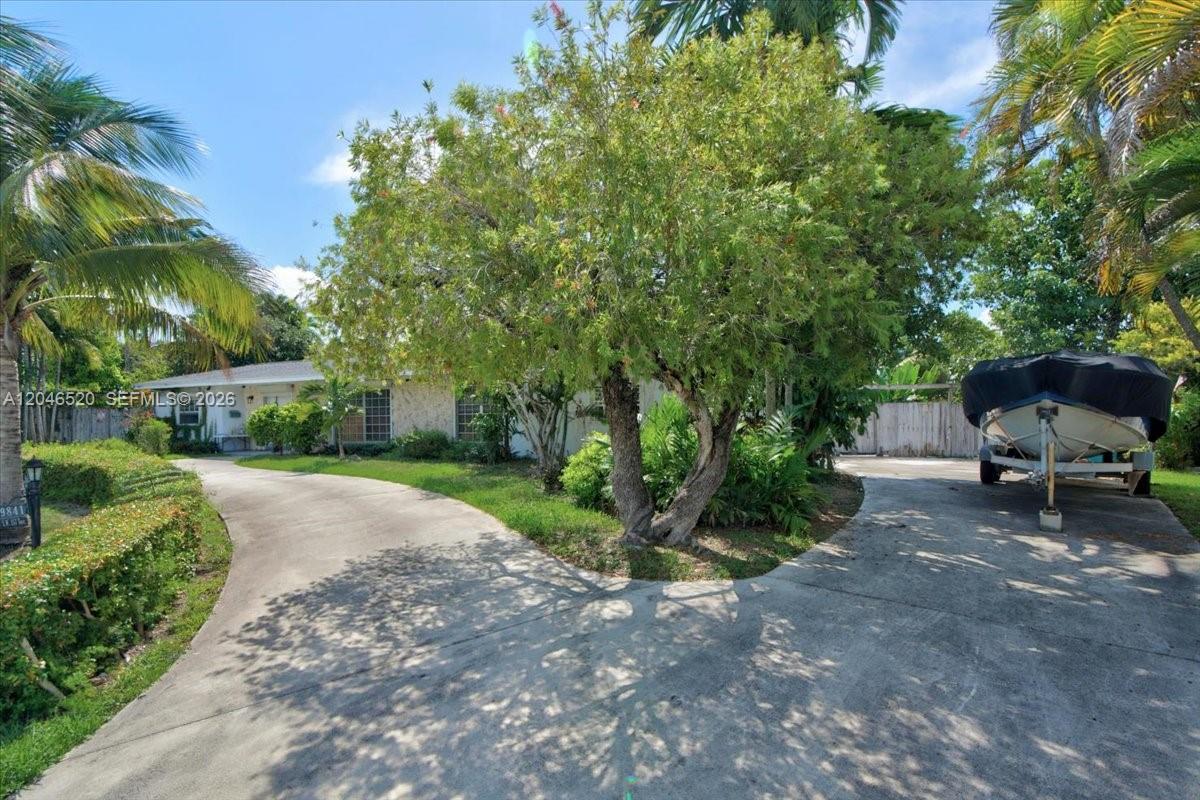 A concrete driveway leads to a single-story house with a boat parked on a trailer — 9841 SW 157th Ter, Miami FL 33157, MIAMI, FL