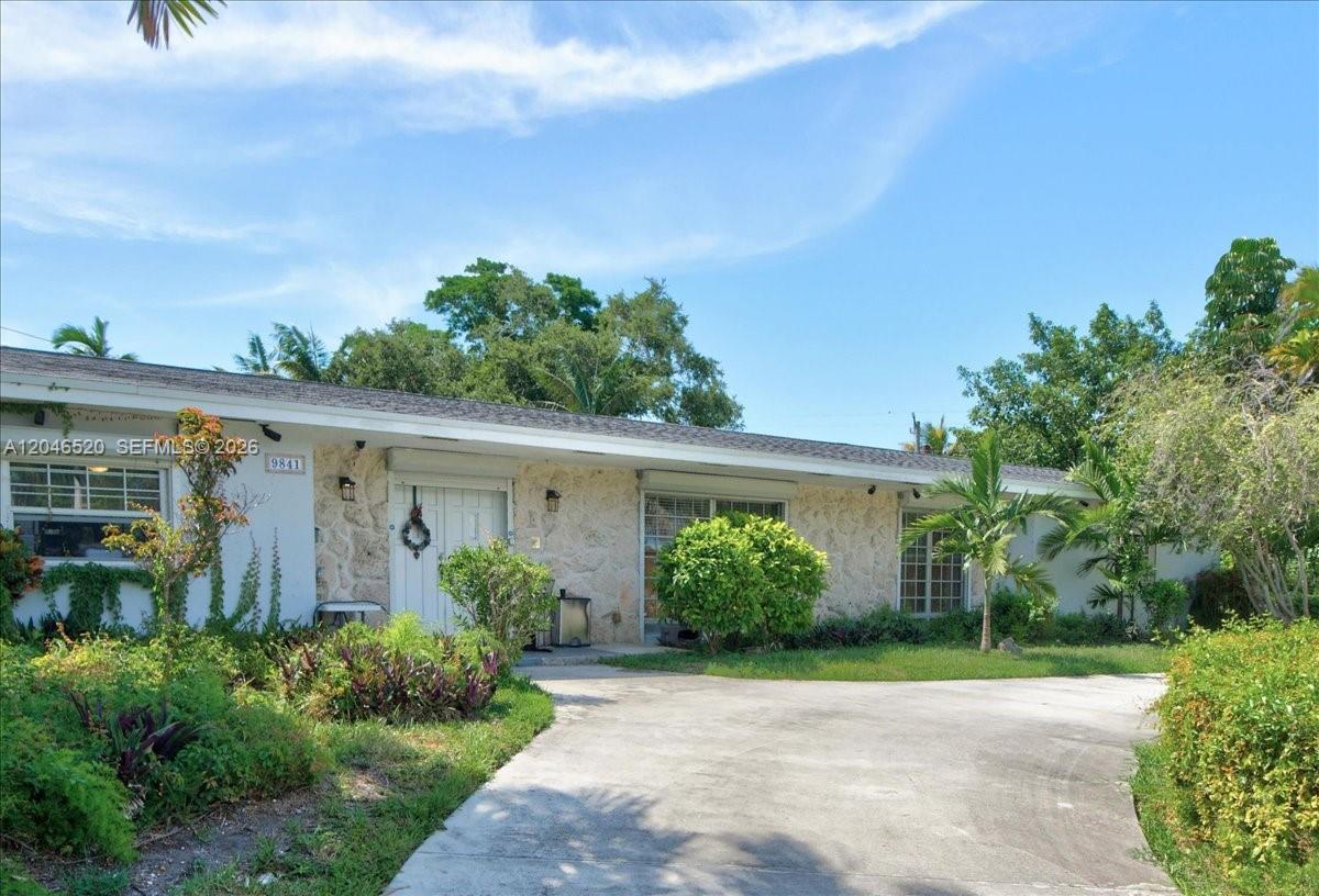 A single-story house with a stone facade, a concrete driveway, and lush landscaping — 9841 SW 157th Ter, Miami FL 33157, MIAMI, FL