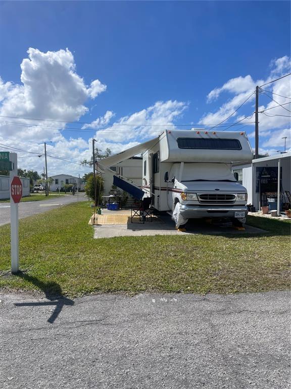 A white recreational vehicle is parked on a concrete pad with an extended awning — 144 PENNSYLVANIA STREET, PALMETTO, FL