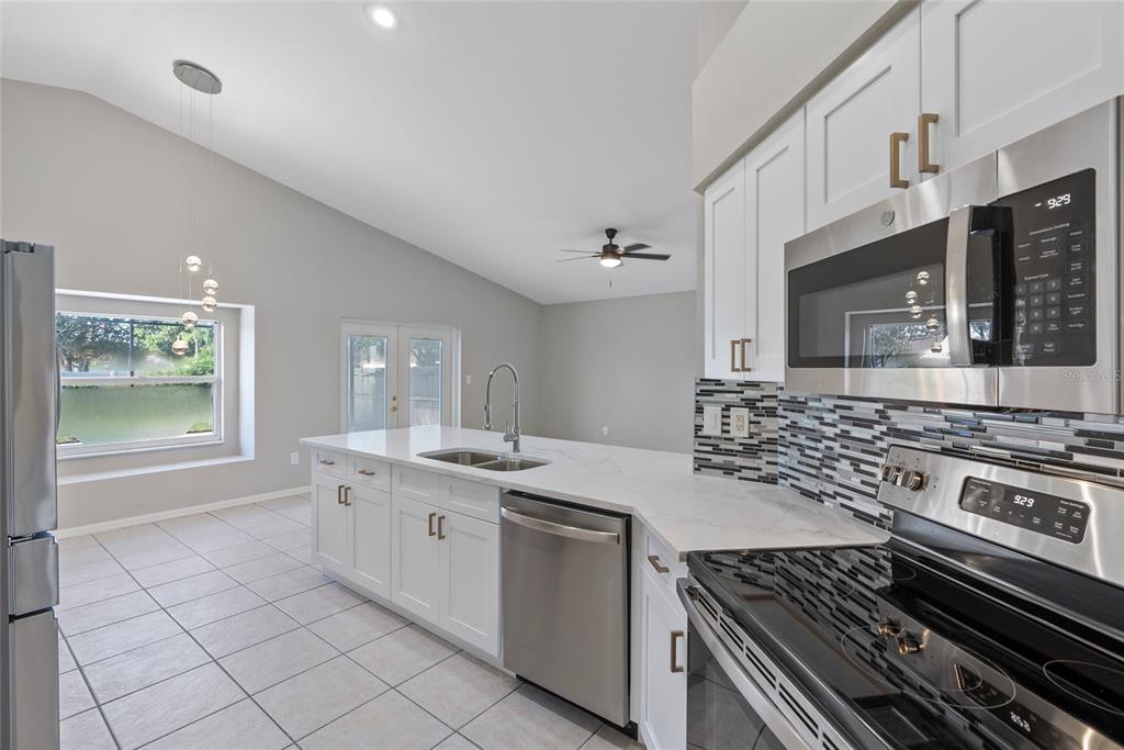 A kitchen with white cabinets, stainless steel appliances, and a view of a pond outside — 1831 ERIN BROOKE DRIVE, VALRICO, FL