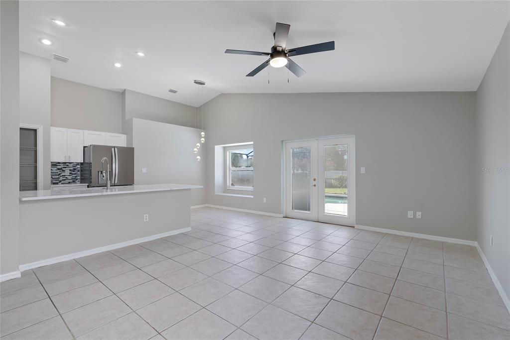 An open-concept kitchen and living area features tile flooring, white cabinets, and glass doors — 1831 ERIN BROOKE DRIVE, VALRICO, FL
