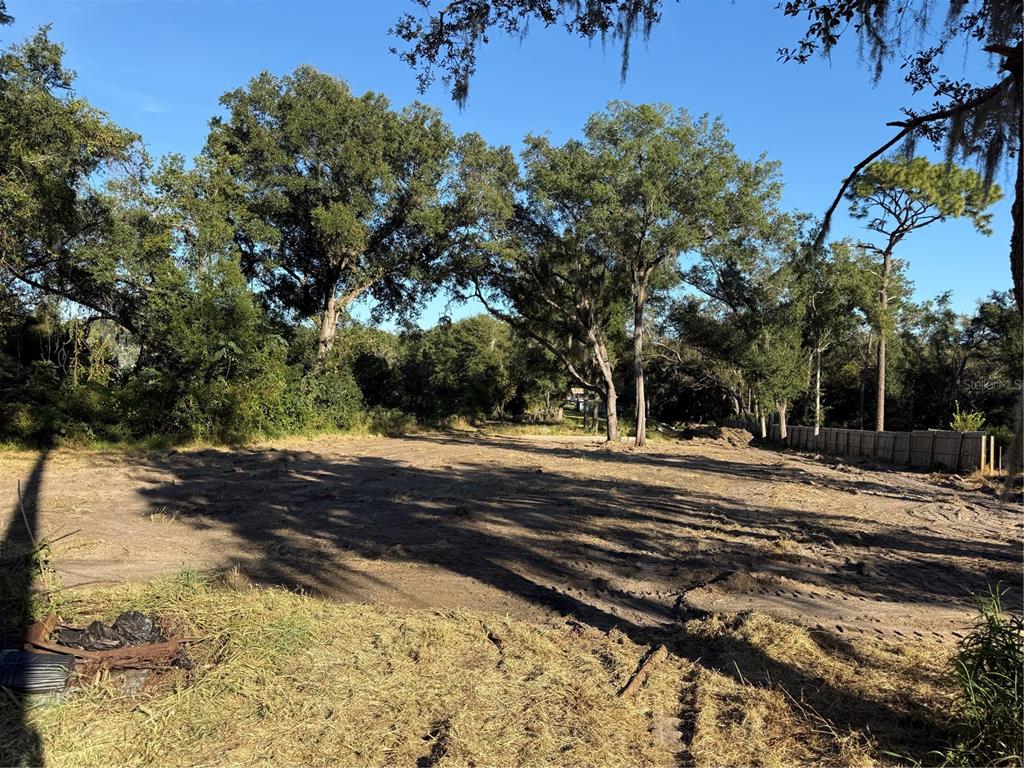 A cleared, level dirt lot is surrounded by mature trees and a wooden fence — 1621 CLARCONA ROAD, APOPKA, FL