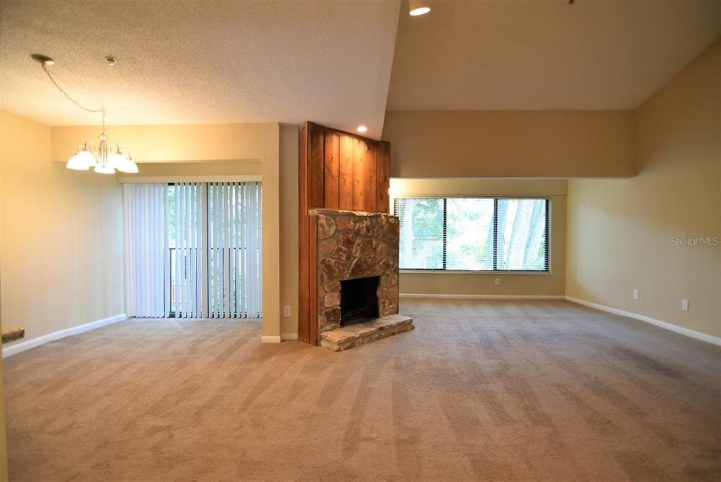A living room features beige carpeting, a stone fireplace, and a dining area with sliding doors — 1068 E MICHIGAN STREET UNIT B, ORLANDO, FL