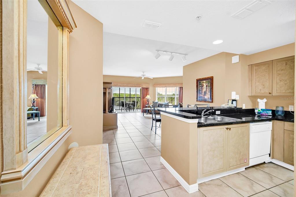 A kitchen with dark countertops and light cabinets overlooks an open living area with tile — 8815 WORLDQUEST BOULEVARD UNIT 2403, ORLANDO, FL
