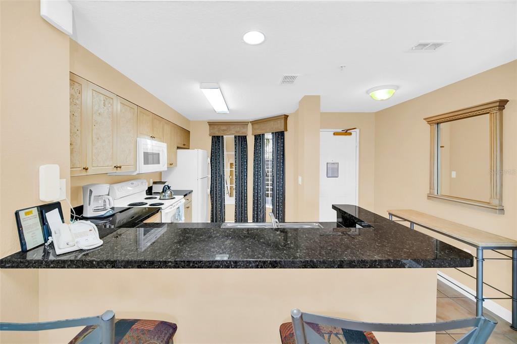 A kitchen with dark granite countertops, light wood cabinets, and a breakfast bar — 8815 WORLDQUEST BOULEVARD UNIT 2403, ORLANDO, FL