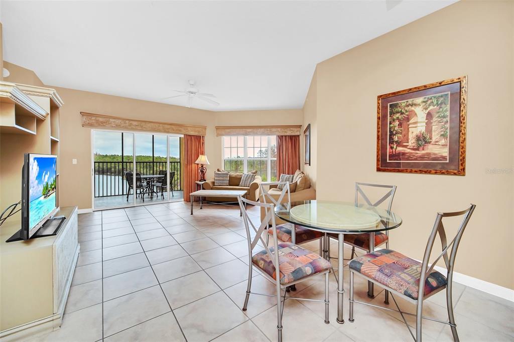 A living and dining area with tile floors, a glass table, and a balcony view — 8815 WORLDQUEST BOULEVARD UNIT 2403, ORLANDO, FL