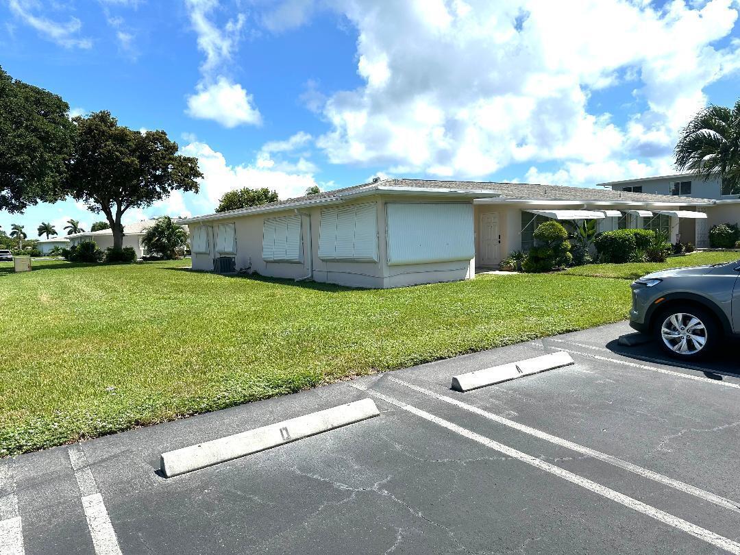 A single-story building with white exterior walls and closed hurricane shutters sits near a parking lot — 135 South Boulevard # A, Boynton Beach FL 33435, BOYNTON BEACH, FL