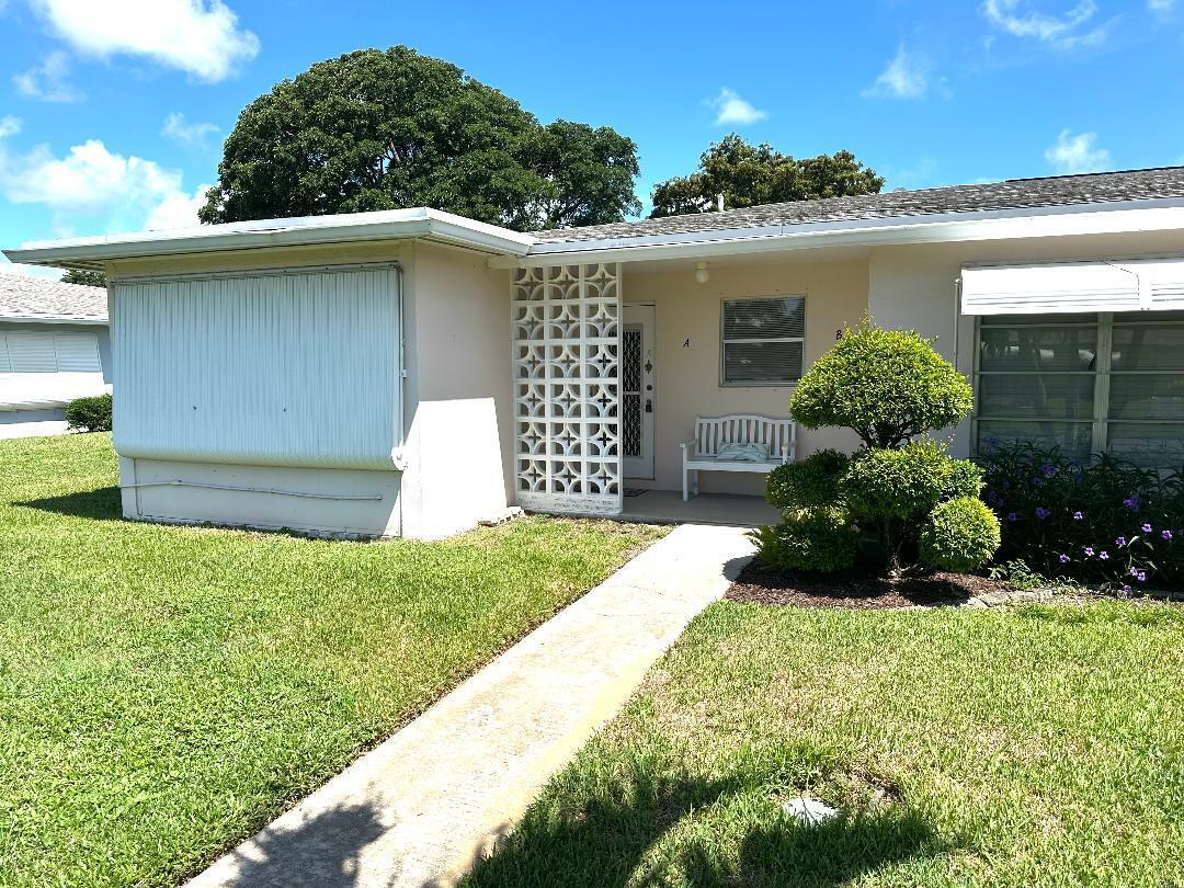 A single-story house exterior features a concrete walkway, a decorative screen wall, and landscaping — 135 South Boulevard # A, Boynton Beach FL 33435, BOYNTON BEACH, FL