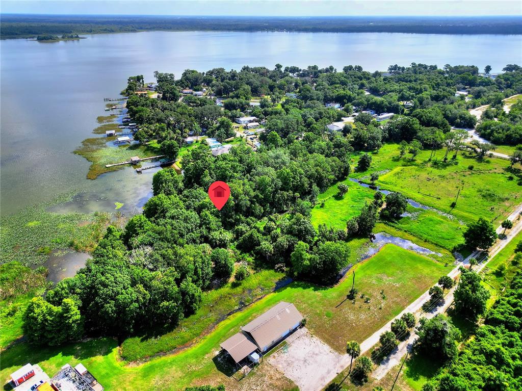 An aerial view shows a wooded lot marked with a red pin near a lake — 1001 W LAKE MARION ROAD, HAINES CITY, FL