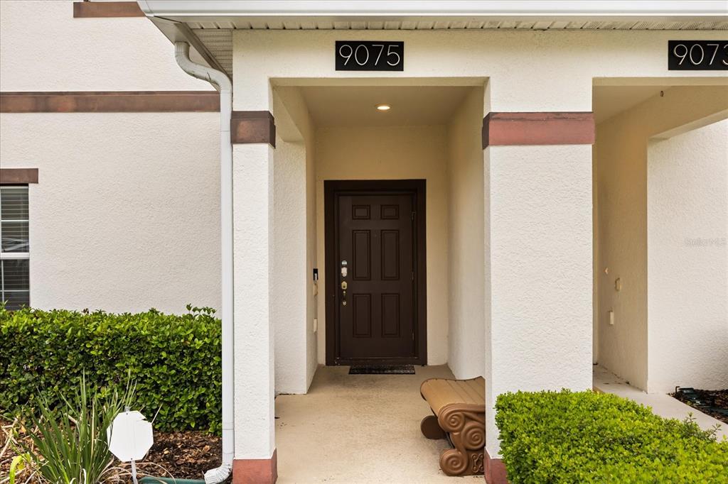 The exterior of a two-story stucco townhouse features a tiled roof and palm trees — 9075 DOGLEG DR, DAVENPORT, FL