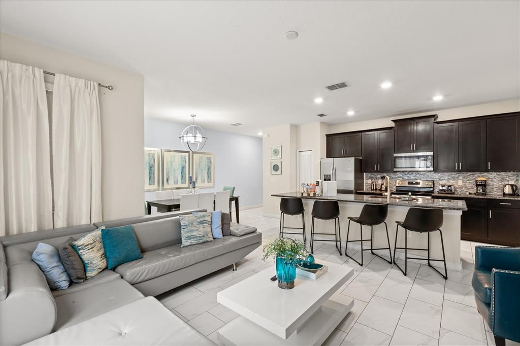 A living room with a gray sectional sofa, white coffee table, and white tile flooring — 9075 DOGLEG DR, DAVENPORT, FL