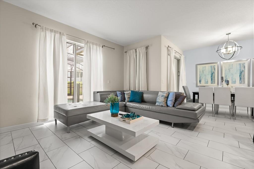 An open-concept living room and kitchen featuring dark cabinetry, a gray sectional, and tile flooring — 9075 DOGLEG DR, DAVENPORT, FL