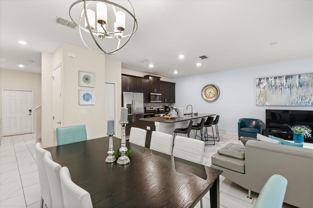 A kitchen features dark wood cabinets, stainless steel appliances, a granite island, and bar seating — 9075 DOGLEG DR, DAVENPORT, FL