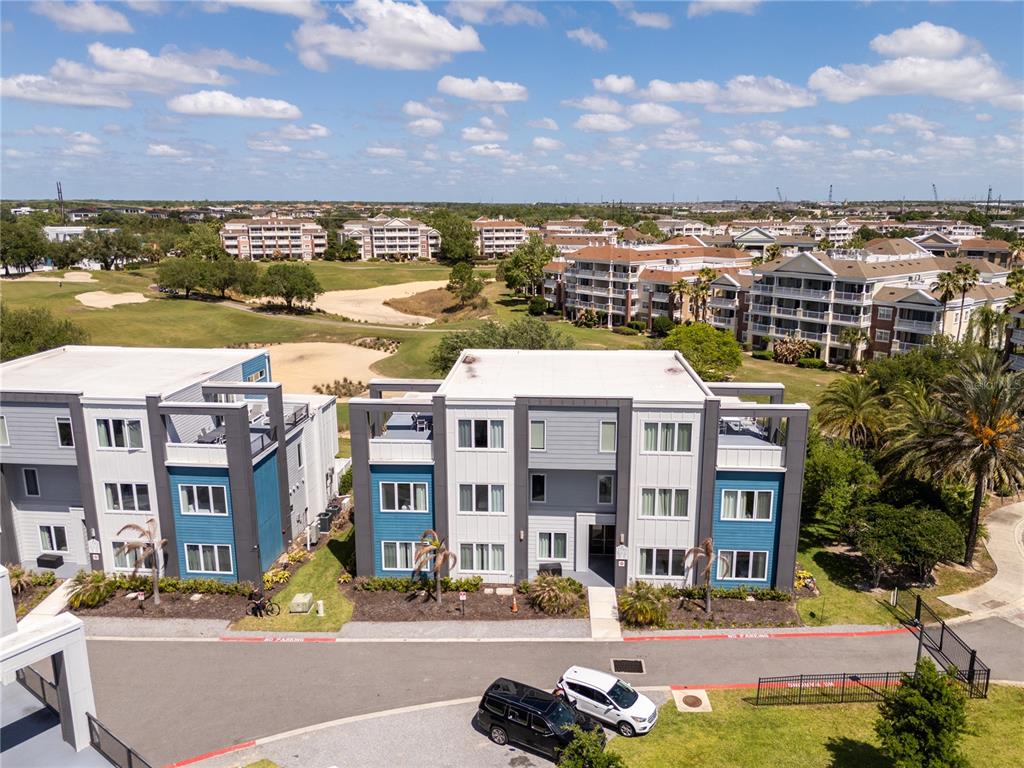 An aerial view shows modern apartment buildings situated next to a golf course — 7740 SANDY RIDGE DRIVE UNIT 247, REUNION, FL