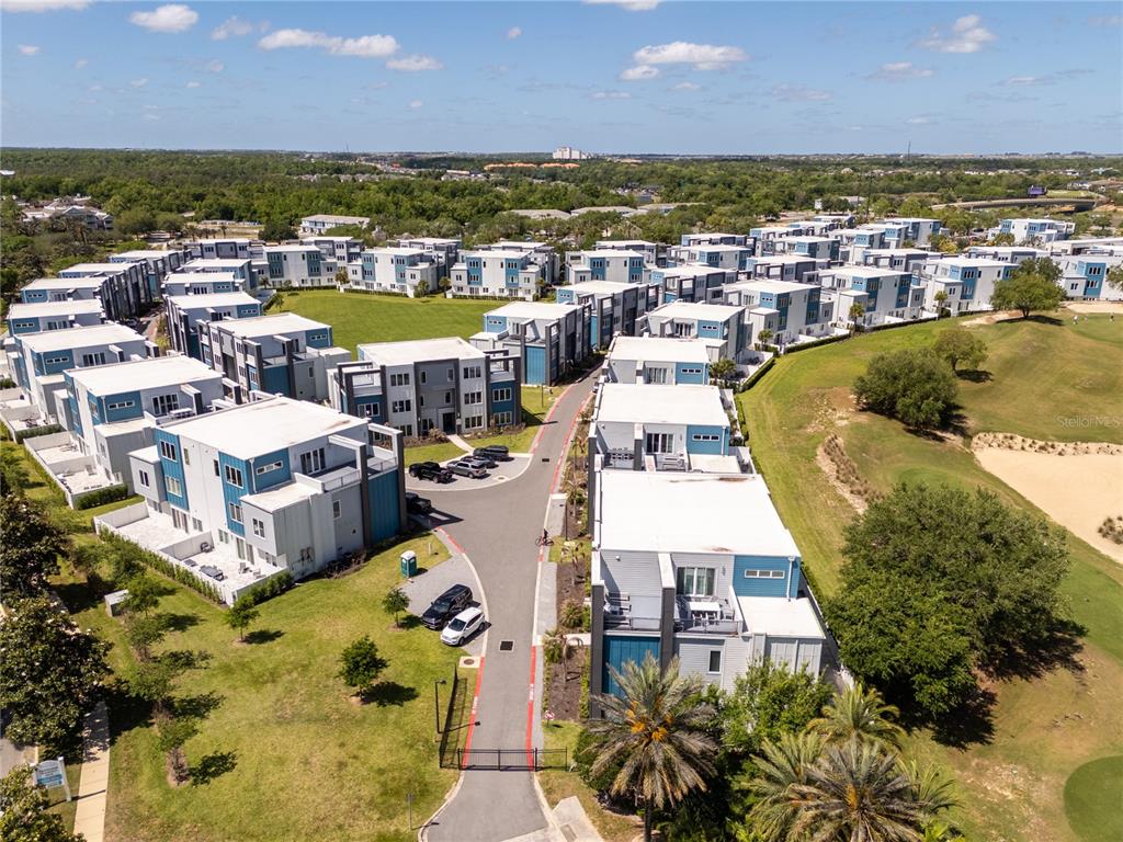 An aerial view shows a modern residential complex with flat-roofed buildings and a paved road — 7740 SANDY RIDGE DRIVE UNIT 247, REUNION, FL