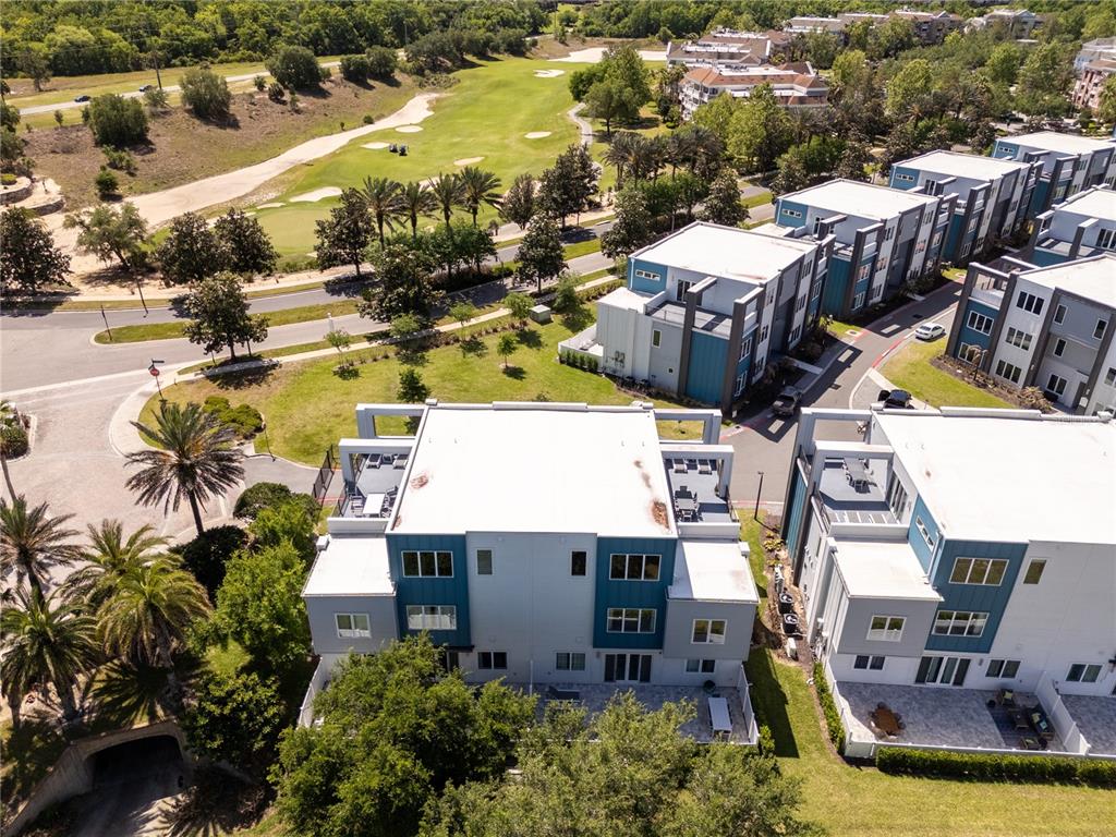 An aerial view shows modern multi-story townhomes with flat roofs and patios near a golf course — 7740 SANDY RIDGE DRIVE UNIT 247, REUNION, FL