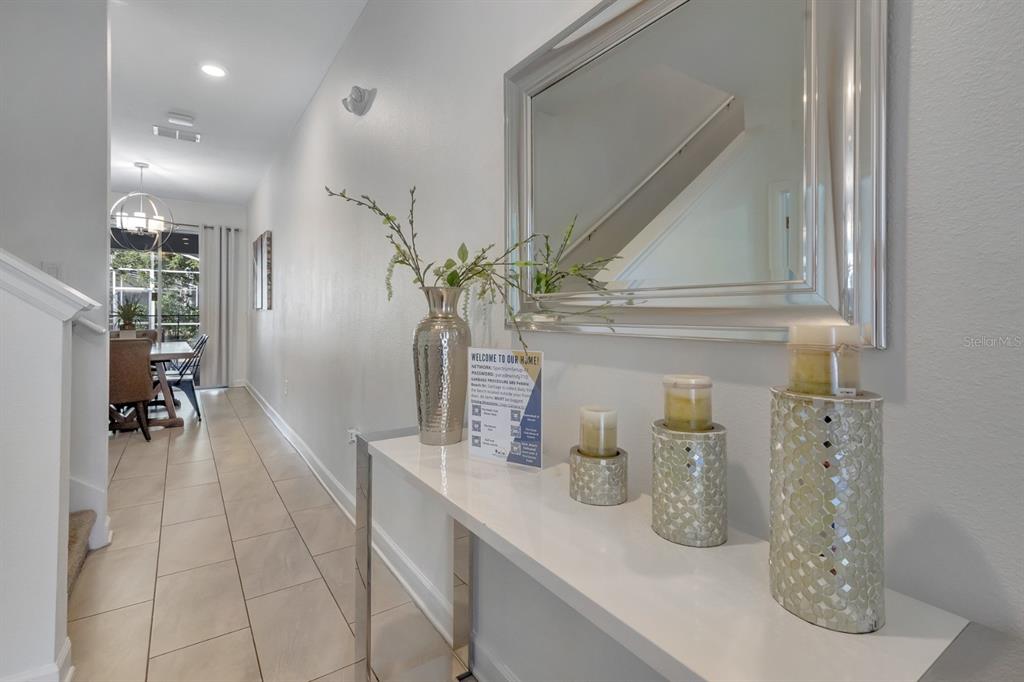 A white console table with decorative items sits in a hallway leading to a dining area — 680 PEBBLE BEACH DRIVE, DAVENPORT, FL