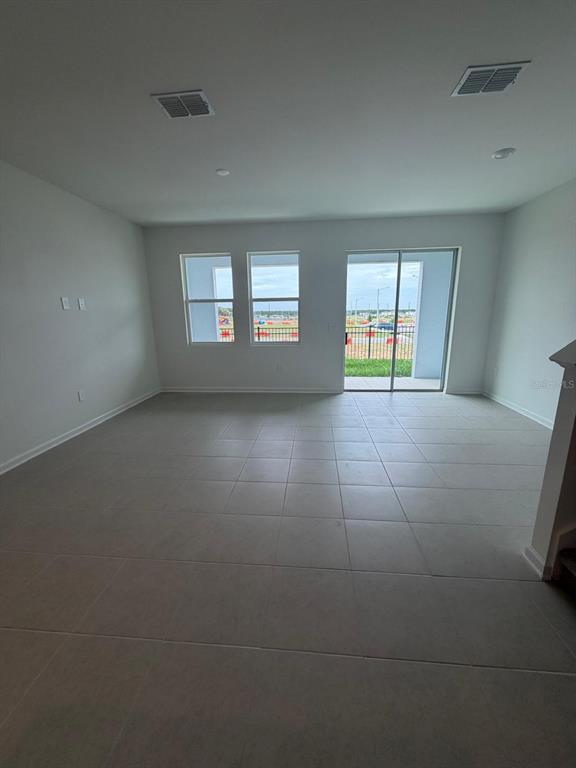 An empty room with light-colored tile flooring, two windows, and a sliding glass door — 3106 KURTZ TERRACE, DAVENPORT, FL