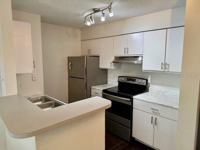 A kitchen with white cabinets, stainless steel appliances, and a peninsula countertop — 2521 GRASSY POINT DRIVE UNIT 101, LAKE MARY, FL