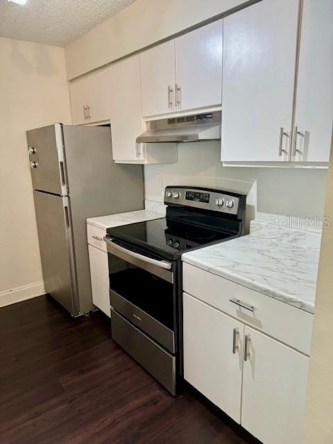 A kitchen features white cabinets, stainless steel appliances, and marble-patterned countertops over dark wood flooring — 2521 GRASSY POINT DRIVE UNIT 101, LAKE MARY, FL