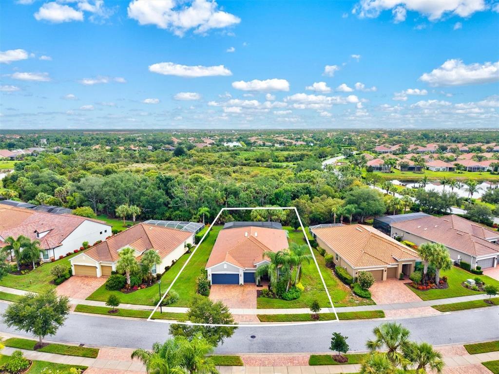 An aerial view shows a single-story house with a tiled roof and a screened pool — 19556 PETRINO STREET, VENICE, FL