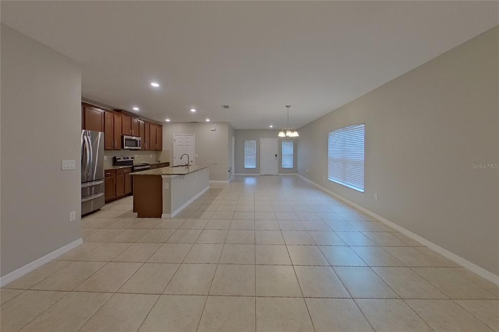 An open-concept kitchen and living area features tile flooring, wood cabinetry, and granite countertops — 417 KESTREL DRIVE, GROVELAND, FL