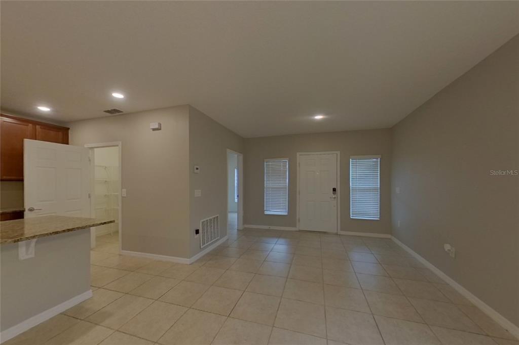 An open-concept living area features light tile flooring, beige walls, and a pantry entrance — 417 KESTREL DRIVE, GROVELAND, FL