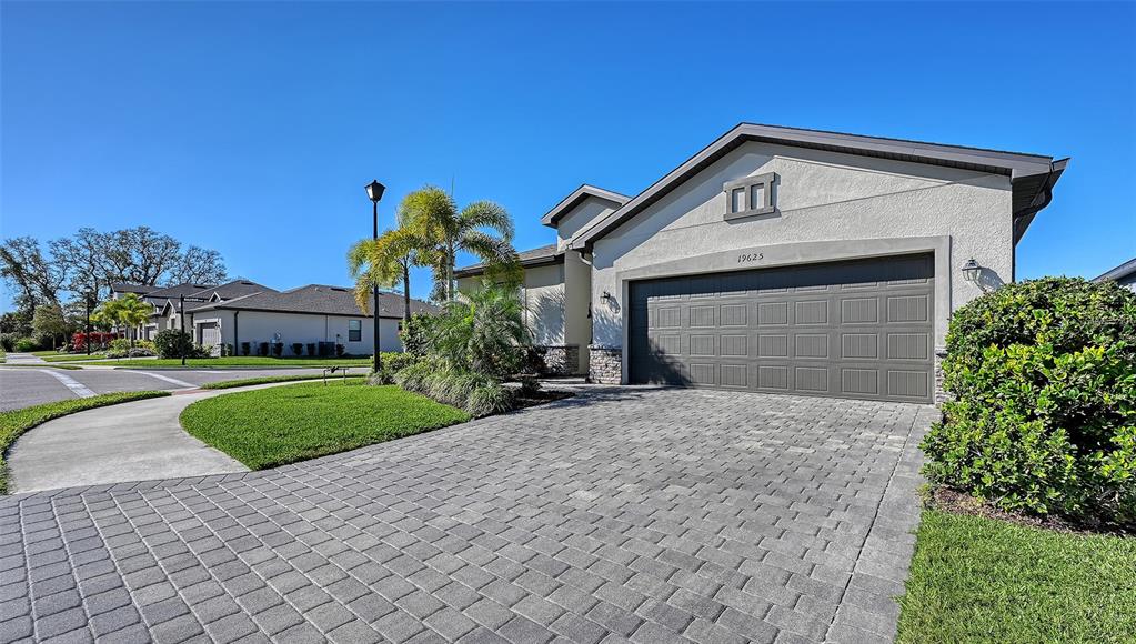 A single-story house with a gray garage door and a paved driveway under a clear sky — 19625 FISHHAWK TRAIL, VENICE, FL