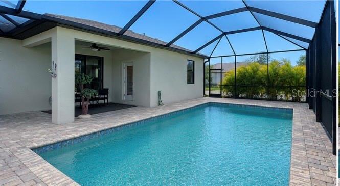 A rectangular swimming pool sits on a paved patio inside a screened-in lanai — 19625 FISHHAWK TRAIL, VENICE, FL