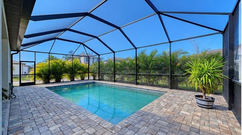 A rectangular swimming pool sits on a paved patio inside a screened-in pool enclosure — 19625 FISHHAWK TRAIL, VENICE, FL