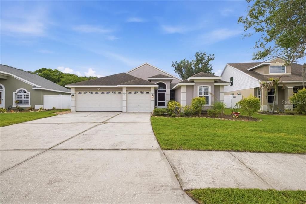 A single-story house with a two-car garage and a concrete driveway under a blue sky — 392 TAVERNIER CIRCLE, OLDSMAR, FL