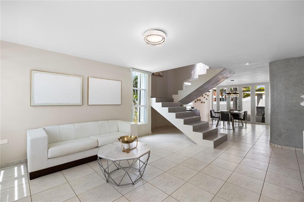 A modern living room features a white sofa, a geometric coffee table, and floating stairs — P-25 PASEO LAS OLAS, DORADO, PR