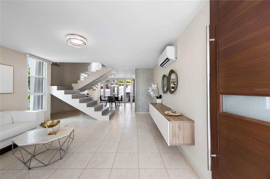 A modern living room features a floating staircase, tile flooring, and a wall-mounted console table — P-25 PASEO LAS OLAS, DORADO, PR