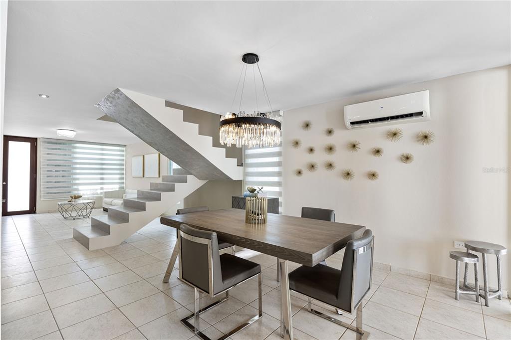 A dining area features a wooden table, modern chairs, a crystal chandelier, and a floating staircase — P-25 PASEO LAS OLAS, DORADO, PR