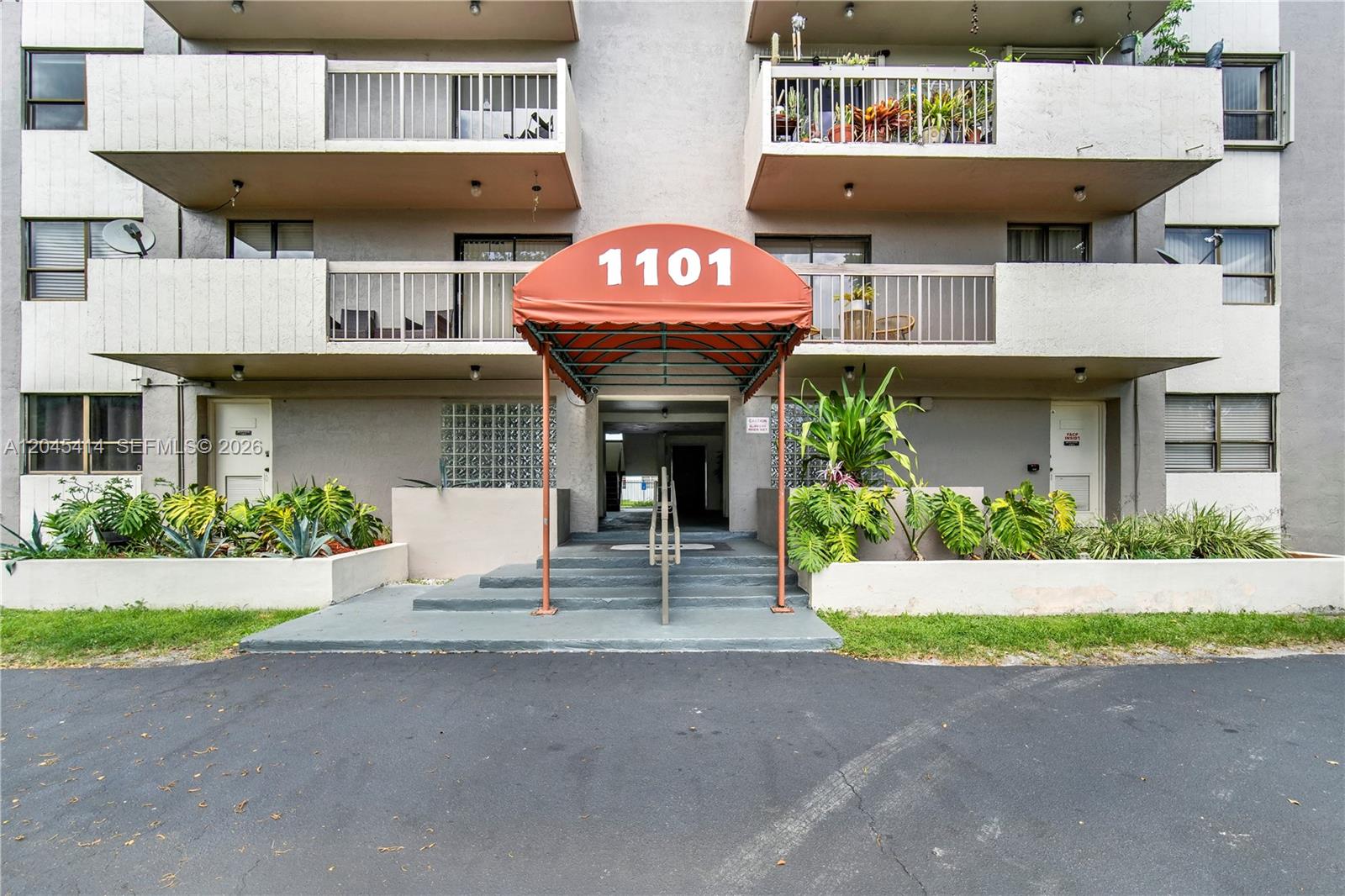 The exterior of a multi-story apartment building features a red awning over the main entrance — 1101 SW 122nd Ave # 205, Miami FL 33184, MIAMI, FL