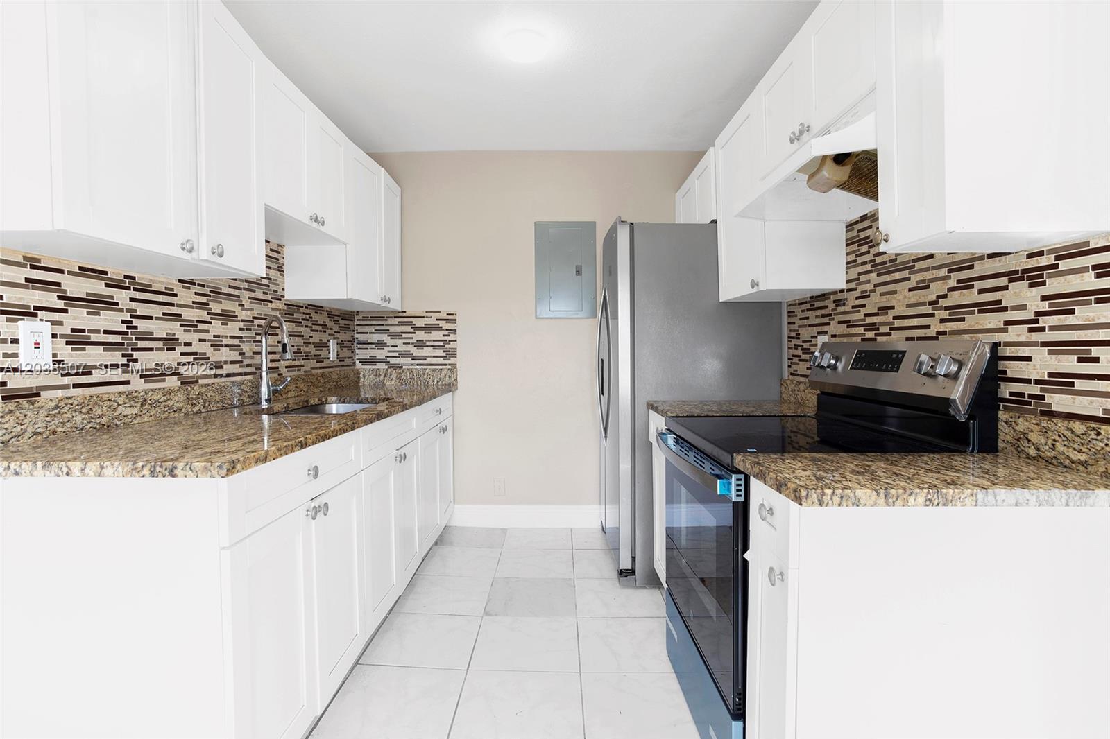 A galley kitchen features white cabinets, granite countertops, a tiled backsplash, and stainless steel appliances — 1333 S Dixie Hwy # 222, Deerfield Beach FL 33441, DEERFIELD BEACH, FL