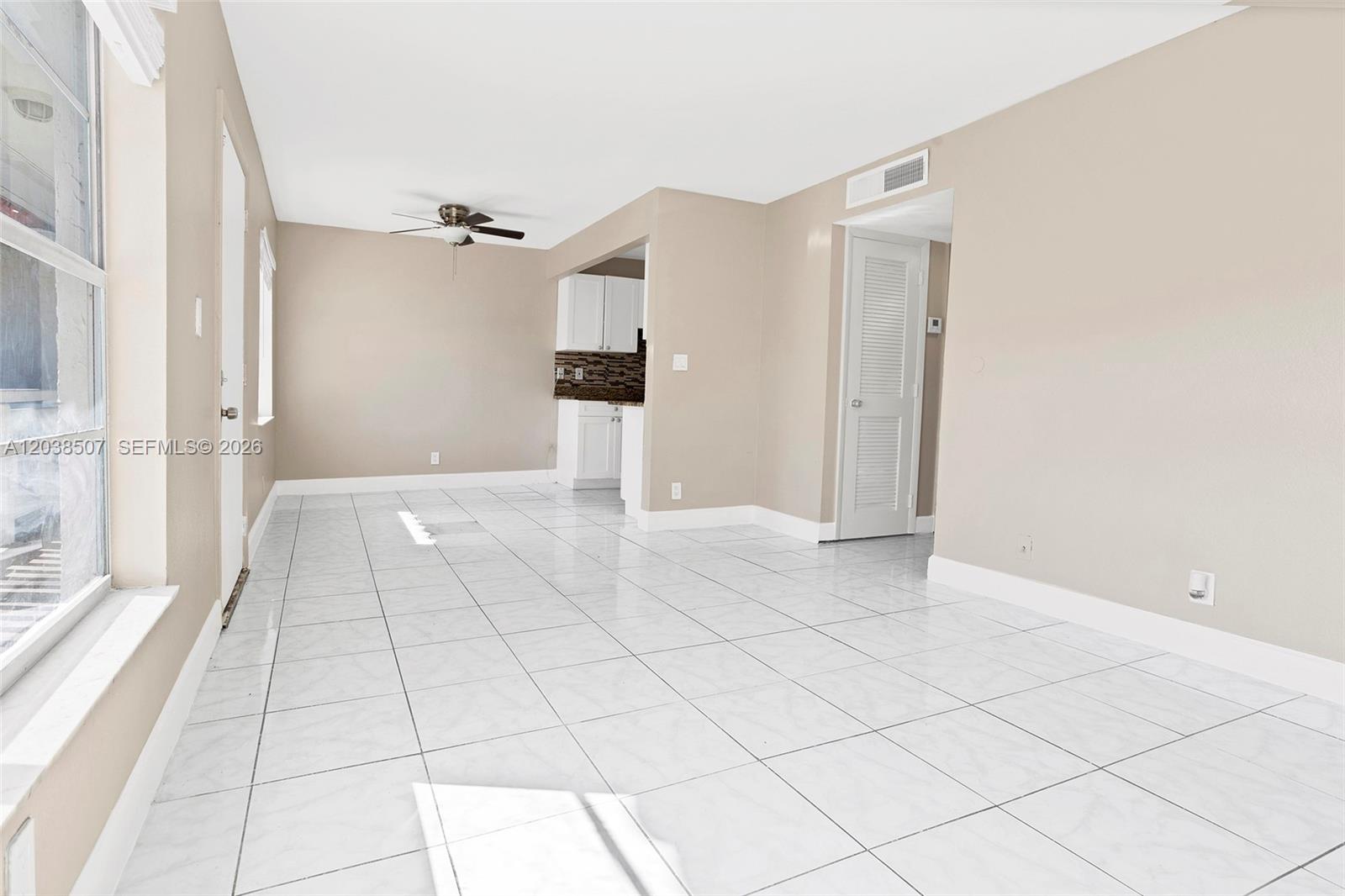 An empty room features white tiled floors, beige walls, and a ceiling fan — 1333 S Dixie Hwy # 222, Deerfield Beach FL 33441, DEERFIELD BEACH, FL