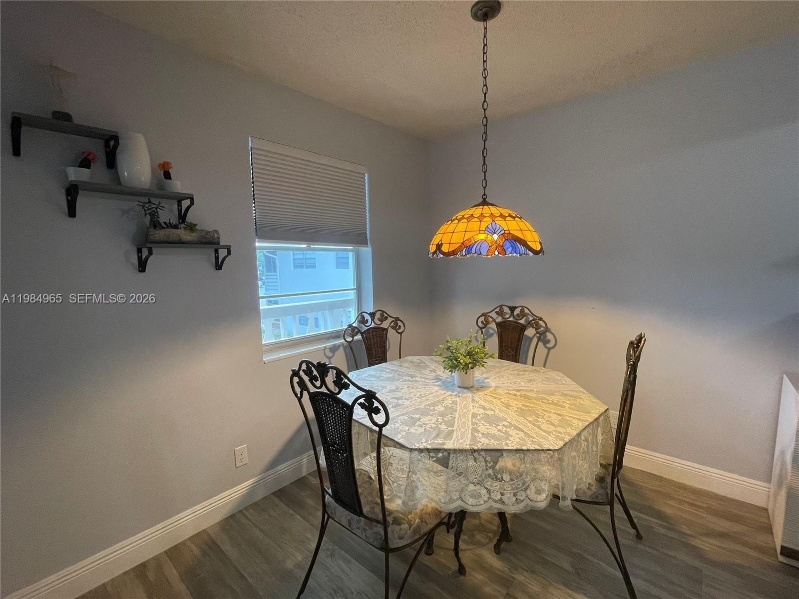 A dining area features a hexagonal table, four metal chairs, and a stained-glass pendant light — 279 Markham M # M, Deerfield Beach FL 33442, DEERFIELD BEACH, FL
