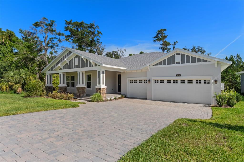 A single-story house with a paved driveway, stone-accented columns, and a three-car garage — 6671 SUMMIT VIEW DRIVE, BROOKSVILLE, FL