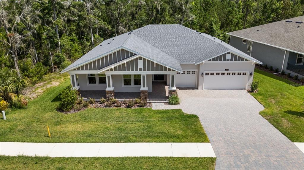 An elevated exterior view of a single-story house with a paved driveway and covered porch — 6671 SUMMIT VIEW DRIVE, BROOKSVILLE, FL