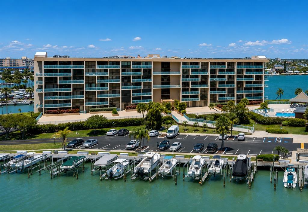 An exterior view of a multi-story apartment building with a parking lot and boat docks — 1 KEY CAPRI UNIT 102W, TREASURE ISLAND, FL