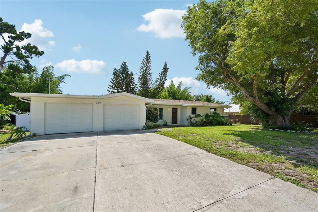 A single-story house with a two-car garage and a large tree in the front yard — 329 BAY VISTA AVENUE, OSPREY, FL