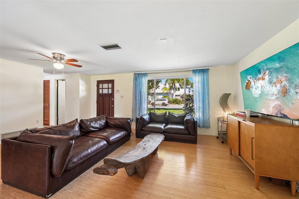 A living room features brown leather sofas, a wooden coffee table, and a wall-mounted television — 329 BAY VISTA AVENUE, OSPREY, FL