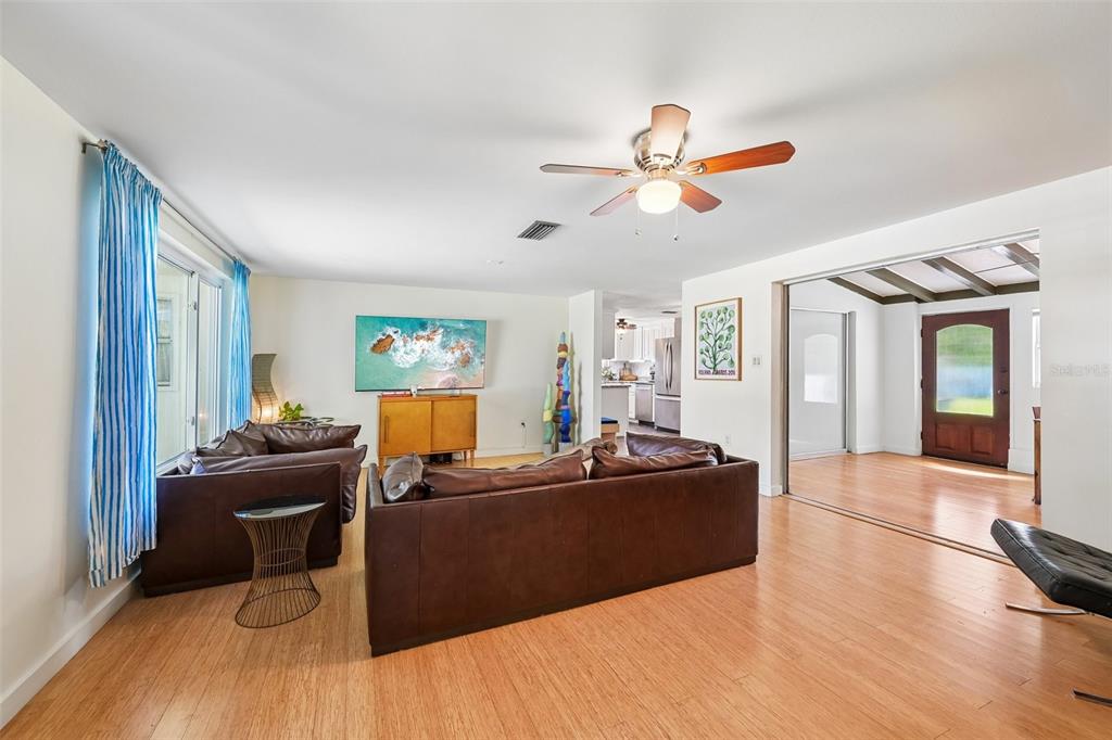 A living room features brown leather sofas, bamboo flooring, and a ceiling fan — 329 BAY VISTA AVENUE, OSPREY, FL
